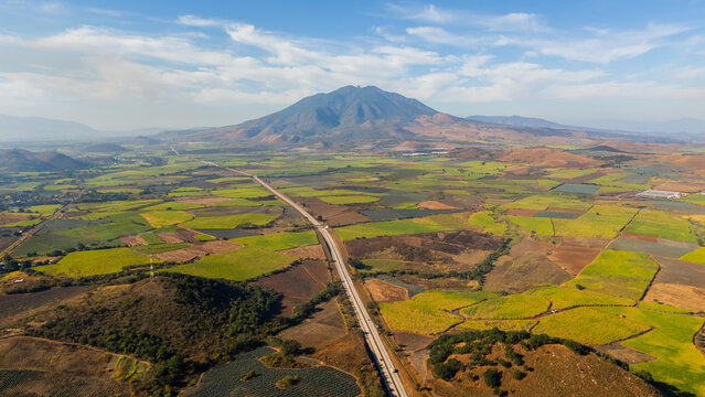Aerial view of Sanganguey volcano and highway crossing huge fields in Tepic, Nayarit. Mexico