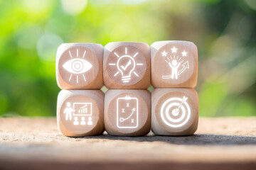 Wooden blocks with icons symbolizing personal growth, success, and development in a natural outdoor setting.