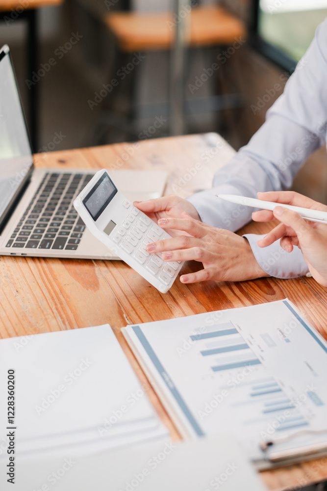Poster close-up of hands using a calculator and laptop, analyzing financial charts and graphs in a professi
