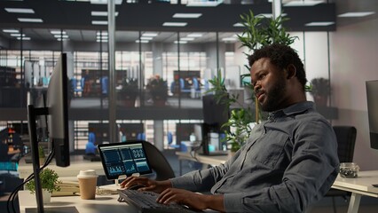 African american employee stretching his arms and back muscles at the office, relaxing on his chair...