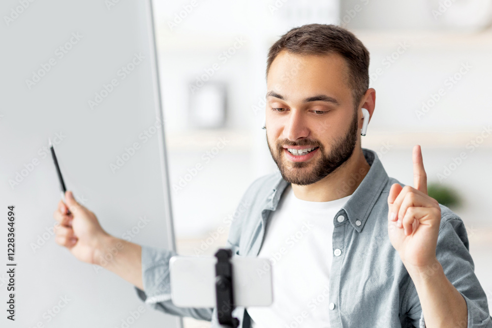 Poster happy male teacher giving online private lesson from home, pointing at empty blackboard with empty s