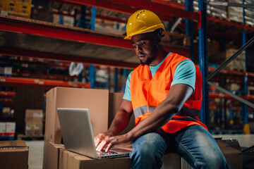Warehouse worker using laptop managing inventory and logistics