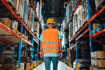 Warehouse worker walking through storage area checking goods and supplies