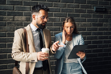 Business people having unexpected problem reading tablet outside office building
