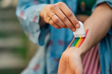 Woman painting rainbow flag on arm celebrating pride month