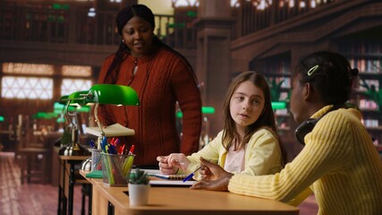 Teacher assisting scholars with class homework for mentoring session, providing academic instruction and support to help with the curriculum. Tutor lecturer gives private lessons. Camera B.