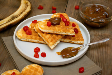 Belgian waffles heart shaped with sweet cherry berries,banana,boiled condensed milk,dessert food.background for Valentines day, womens day, love, romance