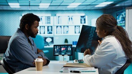 Black male patient bringing x ray test results to medic for scan interpretation, reviewing the...