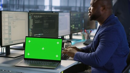 Data center technician using chroma key laptop, maintaining company network infrastructure. Server hub employee ensuring optimal system performance with isolated screen notebook, camera A