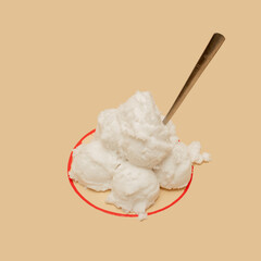 White scoops of fake ice cream in an imaginary red line bowl with a spoon