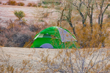 Green tent sitting alone stealth camping in the desert