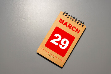 Wooden block calendar with date March 29 on blue yellow backround.