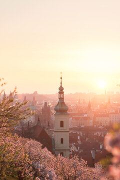 Baroque chapel bell tower steeple at historical part of city on the background of an orange red sunrise sky.