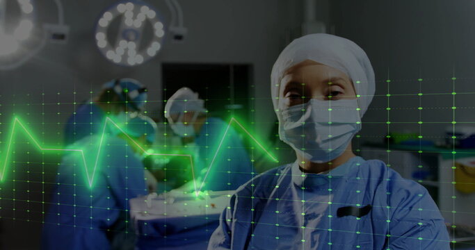 Image of cardiograph over diverse surgeons with face masks in operating room