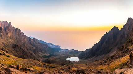 Mountain Valley Reveals a Serene Lake at Sunset with Majestic Peaks and Rugged Terrain