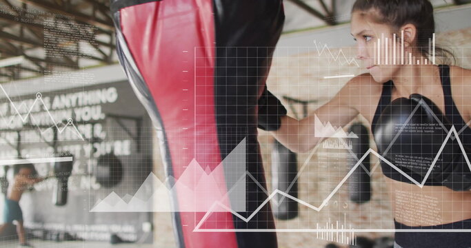 Image of diagrams and data processing over caucasian woman punching boxing bag at gym