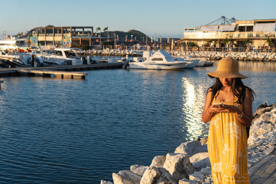 Tourist using smartphone near marina at golden hour
