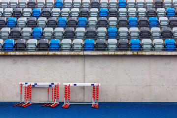 Plastic folding seats at the city stadium. Blue and grey seats on the stands. Running barriers...