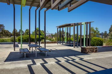 A modern public rest area featuring architectural metal columns, with built-in metal benches...