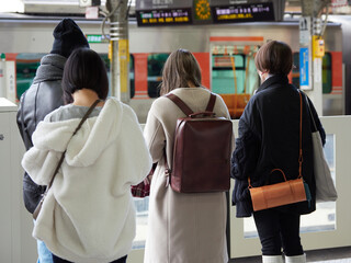 冬の駅のホームで電車待ちの若い女性と人々の姿
