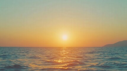 Serene sunset over calm ocean waters with distant mountains and a clear sky