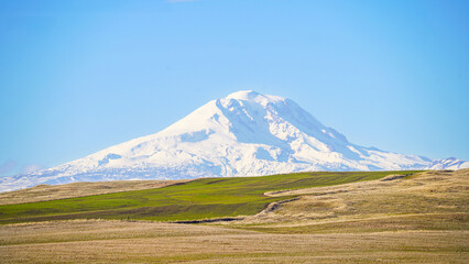 Fototapeta premium Snow capped Mountain over looking farmland