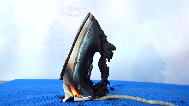 Electrical Short Circuit. Fire socket of electricity plug switch. Burning electric iron. Electric iron in fire. Short circuit in Overloaded. Smoke Burned electric iron. Burning household appliance.