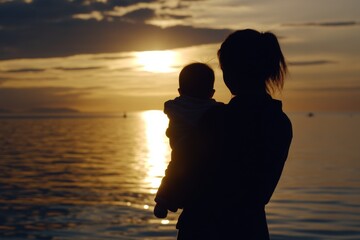 Fototapeta premium Mother and child enjoy a serene sunset by the calm water on a tranquil evening