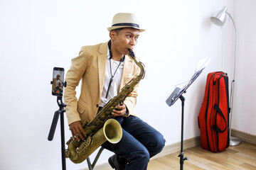 Naklejka premium Side View Of Saxophonist Playing A Music While Recording Vlog Using Smartphone At Music Studio 
