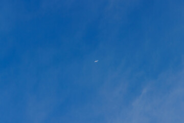 青い空と薄い雲の間を飛ぶ飛行機