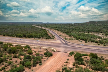 aerial view intersection highway with traffic cars, bus, trucks, on african landscape bush and hills range , new developments in transport , daytime
