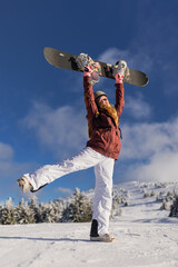 Joyful snowboarder celebrating on a sunny snowy day in the mountains with a bright sky