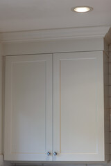 White cabinets with handles in the kitchen, white kitchen cabinet with silver handles against a background of white boot and walls
