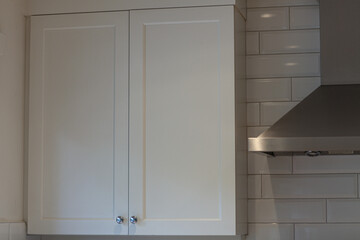 White cabinets with handles in the kitchen, white kitchen cabinet with silver handles against a background of white boot and walls