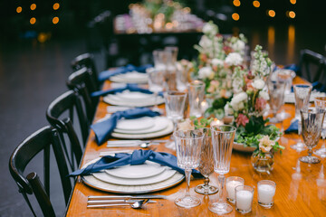 Elegant dining table set for a celebration in an indoor venue with floral centerpieces and soft lighting