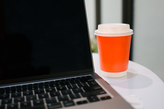 A cup of coffee put on table with laptop in a cafe