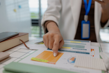 there are a lot if documents pied up on the desk if the data analysis team leader, an employee sits...