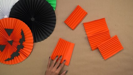 Making Halloween-themed paper rosettes with orange and black folded paper decorations - Powered by Adobe