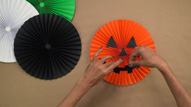Making paper rosettes for Halloween with a festive pumpkin face decoration