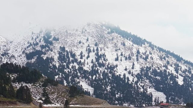 Revealing the Agali Shelter on Mount Dirfis, capturing the snow-covered mountain in the background