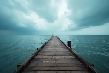 Fototapeta premium Empty wooden pier extends into a moody sea under a cloudy sky , atmosphere, sea