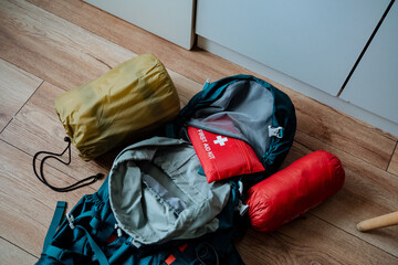 A backpack is currently resting on a sturdy wooden floor, positioned right next to a vibrant red...