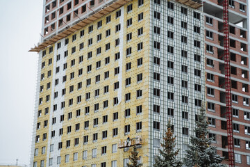 Fototapeta premium A very tall building featuring an extensive number of windows is currently undergoing construction work in the bustling city area, contributing to the urban design and skyline