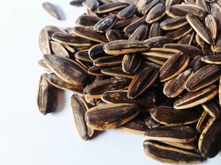 Kuaci or kwatji sunflower seeds. Scattered on a wooden table. Snack on dried and salted sunflower seeds. Selective focus