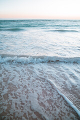 Beautiful ocean waves crash into a sandy beach during sunrise in tropical Punta Cana, Dominican Republic.