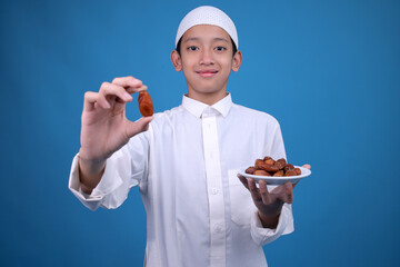 Portrait of Smiling Asian Muslim Boy Eating Date Fruit During Sahur or Breaking The Fast