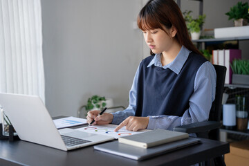Obraz premium Asian businesswoman doing paper work with pen laptop calculator