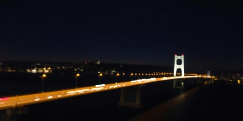 Fototapeta premium Long exposure shot of the Richmond-San Rafael Bridge at night with blurred traffic and twinkling city lights, nighttime roads, California coastline, urban landscape