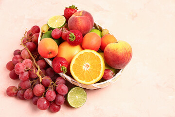 Wicker bowl with different fresh fruits on pink background