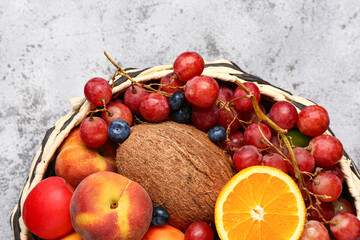 Wicker bowl with different fresh fruits on blue background